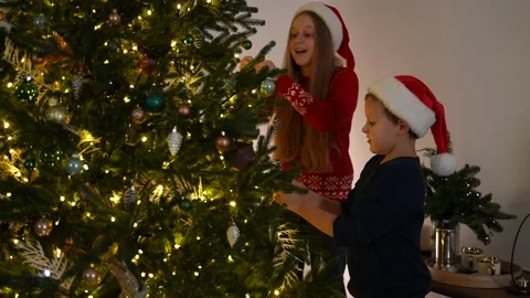 Friendly sibings decorating Christmas tree Видео 166529734