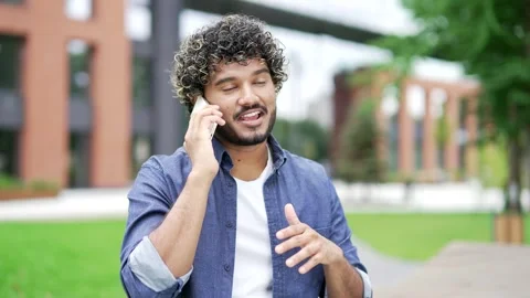 Friendly smiling man talking on mobile phone on street near office building.  Stock Footage 302471940