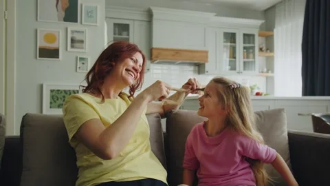 A friendly smiling mother sits on the sofa in the room with her daughter Stock Footage 252880935