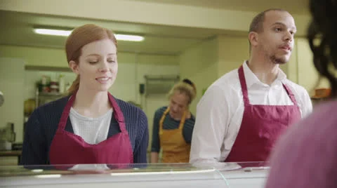 Friendly staff serving customers with a smile at the bakery counter Stock Footage 26238651