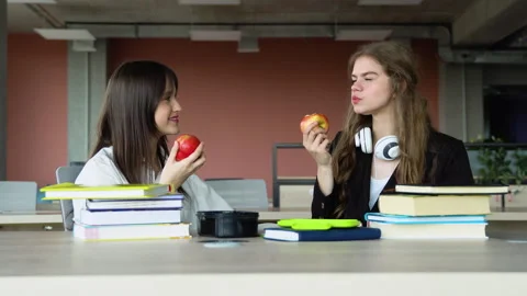 Friendly students having apples at break. Two girls at lunch time in school Stock Footage 243322966
