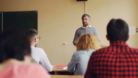 Friendly teacher is talking to his students checking knowledge, young man is Stock Footage 91831152