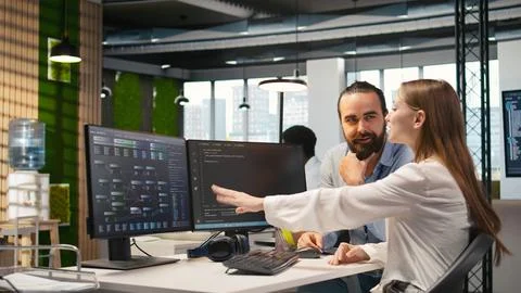 Friendly team leader helping happy young engineer code AI algorithms Stock Photos