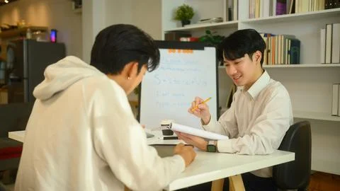 Friendly tutor explaining to student during a private lesson. Education Stock Photos