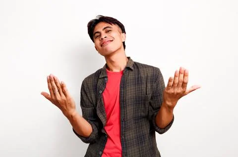 Friendly young Asian man smiling and making welcoming hand gesture to join .. Stock Photos