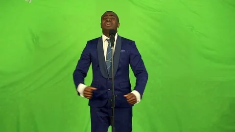 Friendly young black man singing into a microphone on a green background. Stock Footage 74881852