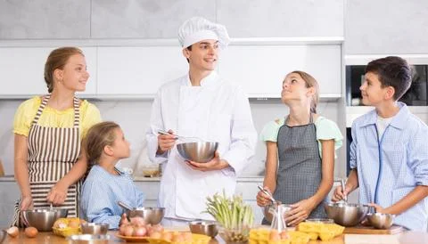 Friendly young chef running culinary courses for group of children Stock Photos