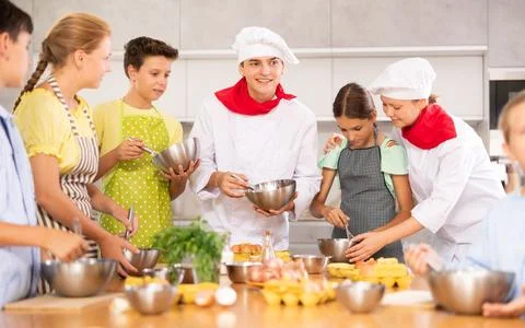 Friendly young chef running culinary courses for group of children Stock Photos