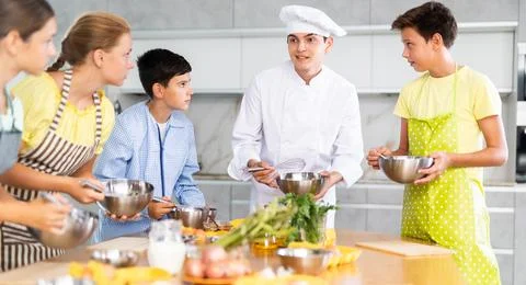 Friendly young chef running culinary courses for group of children Stock Photos
