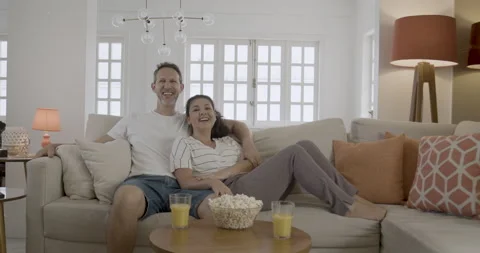 Friendly young couple watching a comedy movie sitting on the sofa. 스톡 동영상 232433669