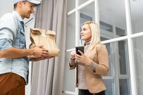 Friendly young delivery man delivering a package Stock Photos