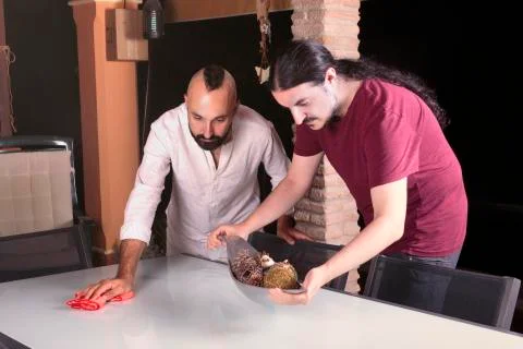 Friendly young men cleaning a table before dinner Stock Photos