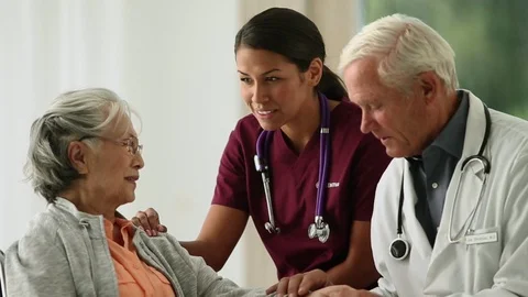 Friendly young nurse comforts an elderly woman as she talks with the doctor. Vidéo 88406625