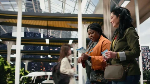 Friends analyzing bus ticket details and smartphone navigation app while walking Stock Footage 340201215