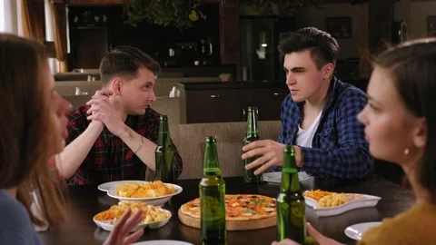 Friends are clinking bottles with beer and eat pizza while resting at pub. Stock Footage 145960756
