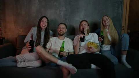 Friends are drinking beer with chips and watching a comedy in front of the TV Stock Footage 197774516