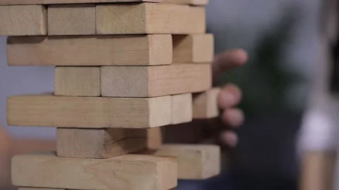 Friends are sitting in the kitchen and playing a board game of jenga. They talk Stock Footage 142890632