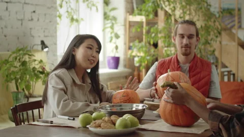 Friends are sitting at the table and discussing how to carve their halloween Stock Footage 170465806