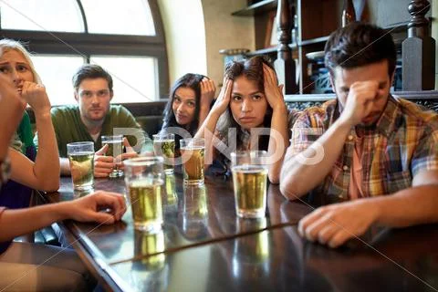 Friends with beer watching football at bar or pub Stock Photos