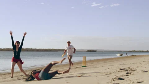 Friends casually playing cricket on the beach with sea and sun in the background Stock Footage 199463664