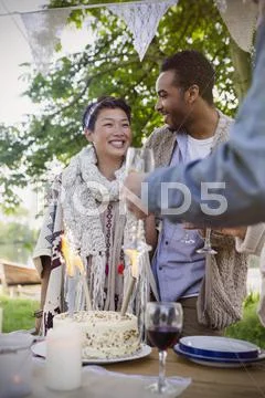 Friends celebrating with birthday cake at patio table Stock Photos