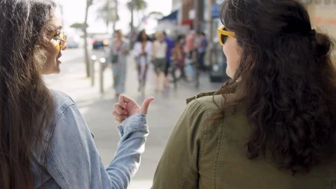 Friends Chat And Walk Down Busy Sidewalk On A Sunny Day In Santa Monica, CA Stock Footage 89957470