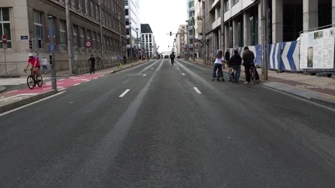 Friends chat in the middle of Rue de la Loi as cyclists pass during Brussels Stock Footage 346784886