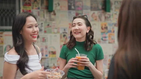 Friends chatting outdoors while enjoying iced beverages and street snacks Stock Footage 319757017