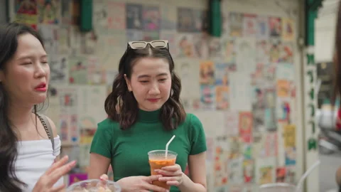 Friends chatting outdoors while enjoying iced beverages and street snacks Stock Footage 319757744