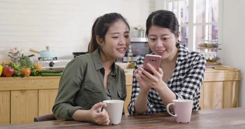 Friends checking phone while relax in kitchen Stock Footage 133399474