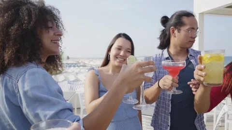 Friends cheers dancing and having fun drink color cocktails in a rooftop bar. We Stock Footage 197047361