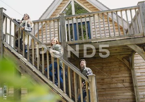 Friends climbing staircase outside wooden cabin Stock Photos