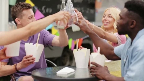Friends clinking drinks and eating at food truck Stock Footage