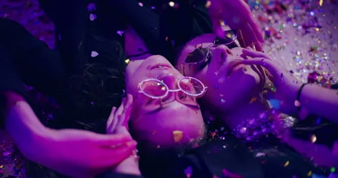 Friends with confetti lying on floor during party Stock Footage 266010736