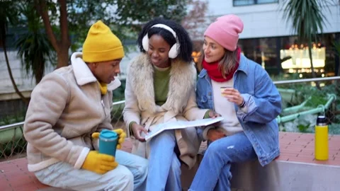 Friends consulting map and drinking hot beverages in winter city Stock Footage 297064184