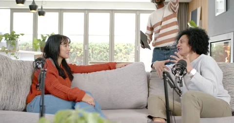Friends on couch, standing man with tablet gesturing up, coordinating seated Stock-Footage 345607702