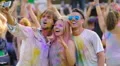 Friends covered in color paint taking photos on smartphone at concert, Holi fest HD Footage