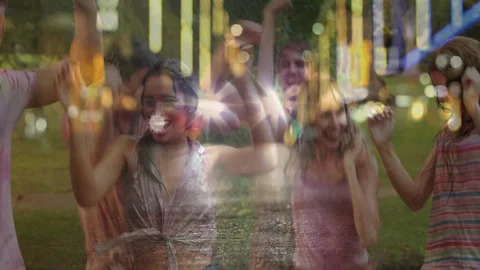 Friends dancing under string lights in park at night, showing event animated Stockbeeldmateriaal 307801014