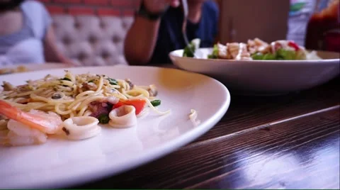 Friends dinner with seafood spaghetti foreground Stock Footage 54265697