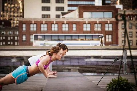 Friends doing push-ups at park against building in city Fotos de archivo