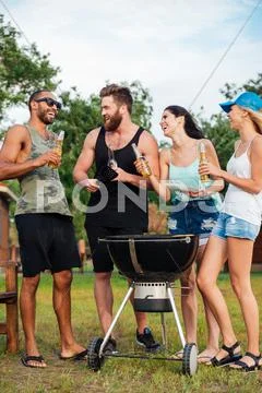 Friends Drinking Beer And Frying Meet On Barbeque Grill Outdoors