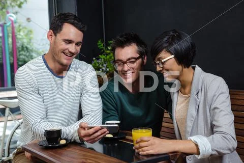 Friends Drinking Coffee And Orange Juice While Looking At Smartphone