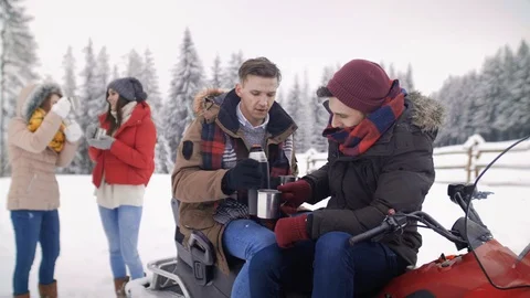 Friends drinking tea and sitting on snowmobile  動画素材 87729151