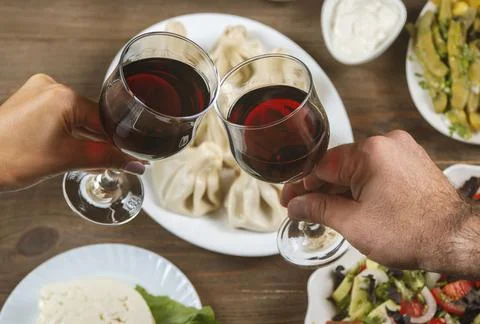 Friends drinking wine over table served with traditional Georgian dishes - ,  Stock Photos