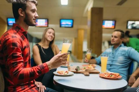 Friends drinks and eats pizza in bowling club Foto stock