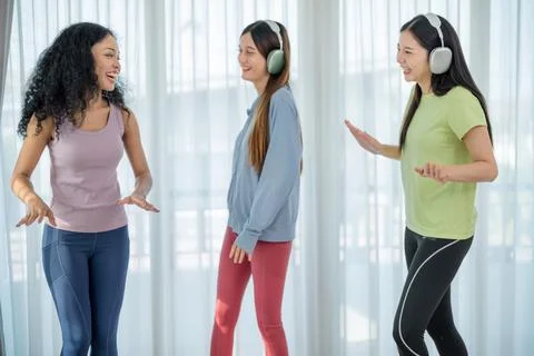 Friends enjoy dancing together while wearing headphones in a bright indoor .. Stock Photos