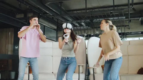 Friends enjoy virtual reality dancing together in a modern indoor space during a Video stock 330689764