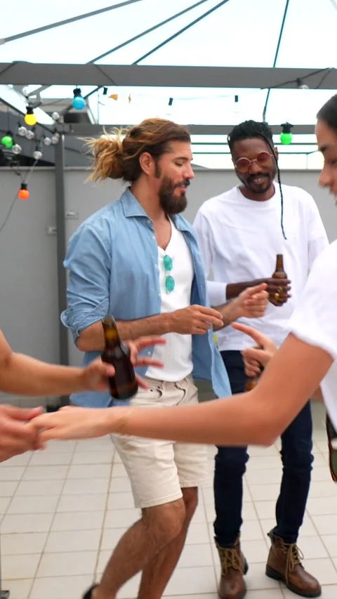 Friends enjoying drinks and dancing at rooftop party Stock Footage 311801060