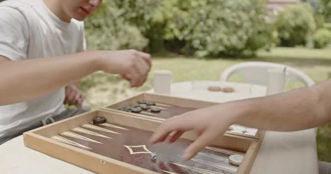 Friends enjoying a game of backgammon outside. The focus is on their hands as Stock Footage 280570156