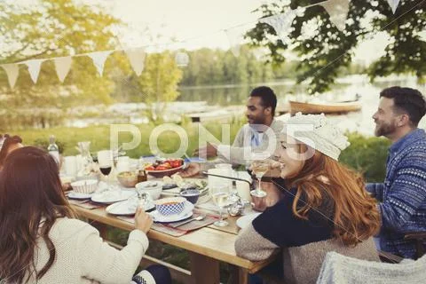 Friends enjoying lunch at lakeside patio table Stock Photos